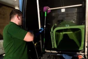 A man cleaning the exterior of a green truck.