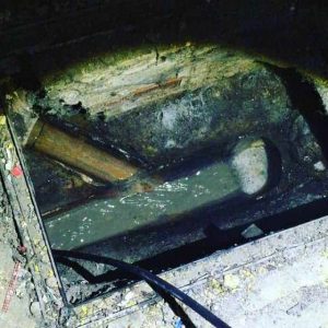 Drain Unblocking, An exterior hole in the ground with a pipe for commercial cleaning purposes.