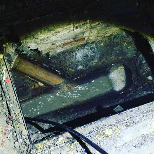 Drain Unblocking, An exterior hole in the ground with a pipe for commercial cleaning purposes.