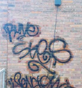 Graffiti on the side of a brick building requiring Exterior Cleaning.