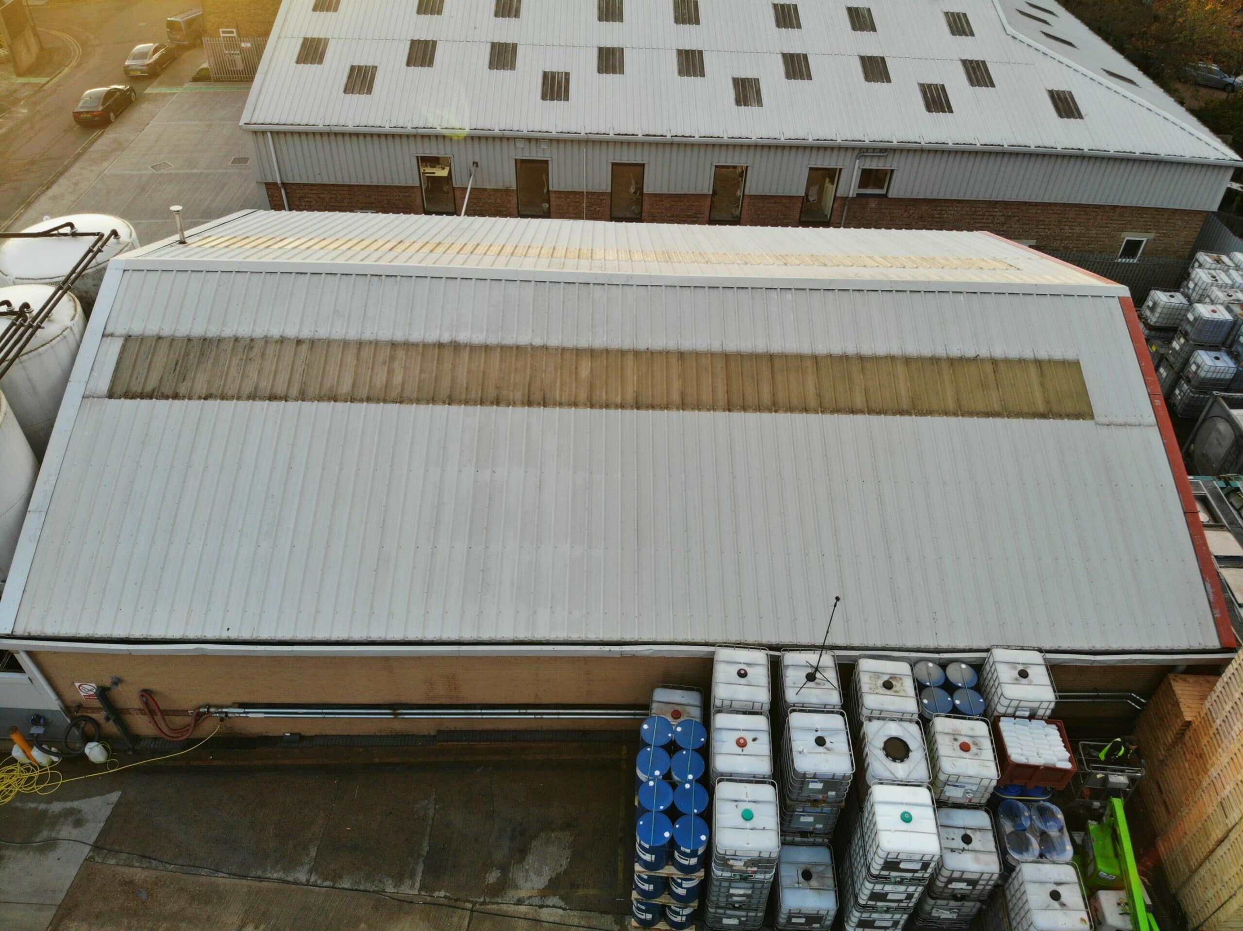 An aerial view of a large warehouse undergoing roof cleaning.