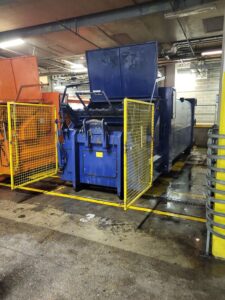 Compactor Cleaning, A blue and orange machine in a garage used for exterior cleaning.