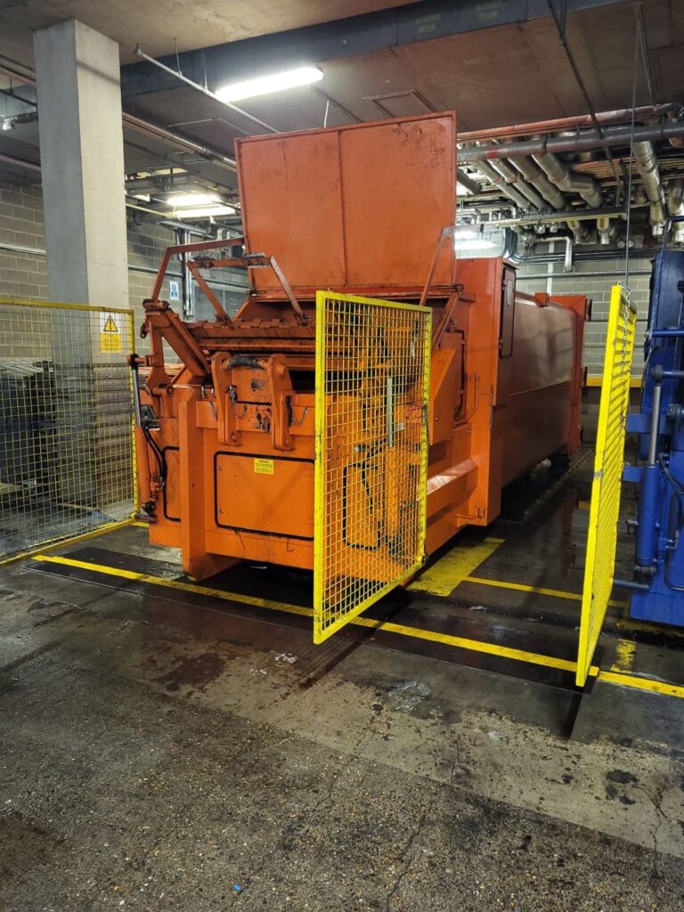 A large orange machine for commercial cleaning sitting in a warehouse.