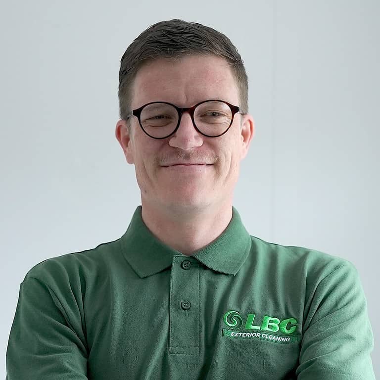 A man in glasses wearing a green polo shirt specializing in Exterior Cleaning.